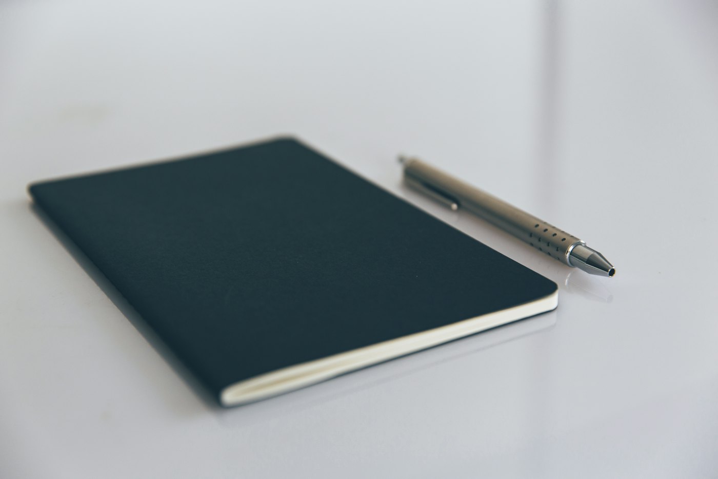 Un carnet fermé et un stylo posés sur un bureau clair