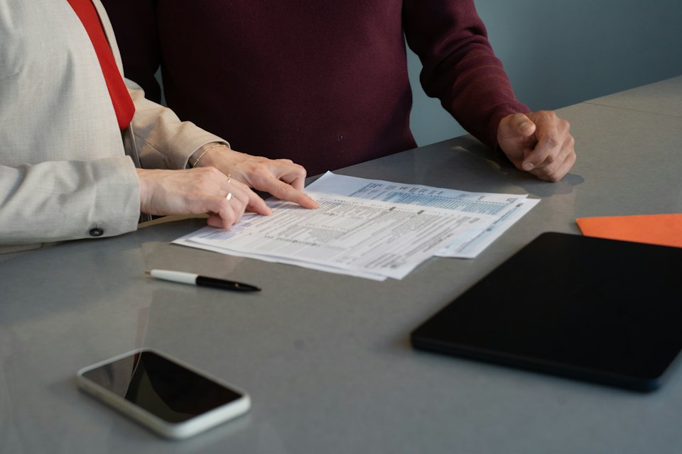 Deux personnes examinent ensemble des documents imprimés sur une table