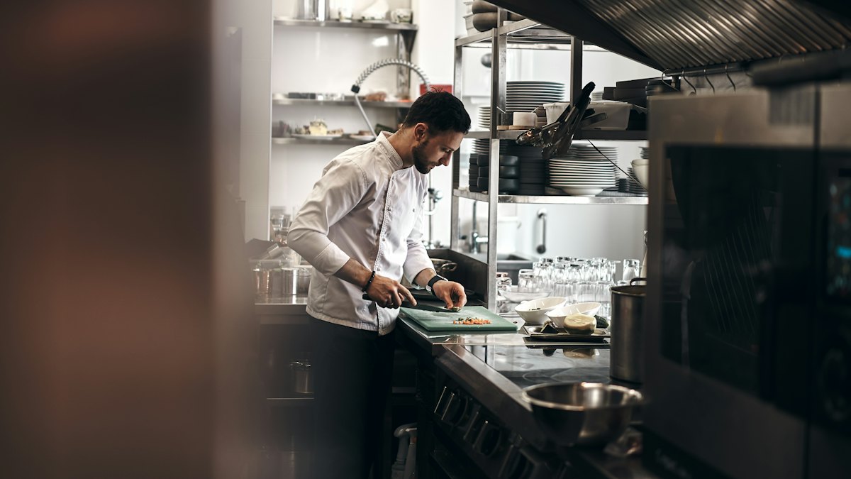 Un cuisinier dresse une assiette dans la cuisine d’un restaurant