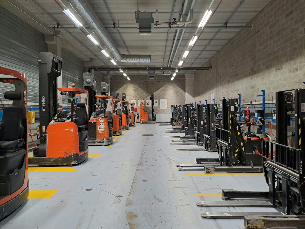 Entrepôt logistique avec une rangée de transpalettes électriques alignés